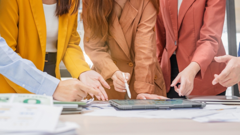 Team reviewing customer and market data on a tablet to apply analytical skills in strategy planning