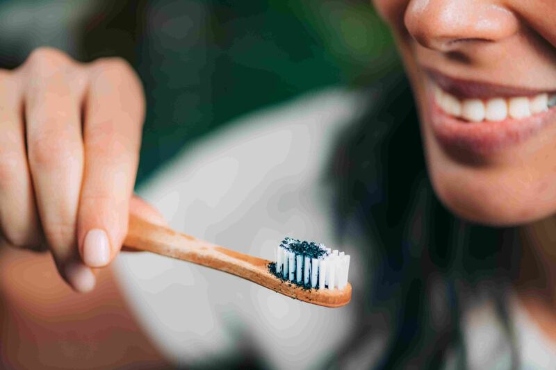 Person holding a toothbrush with whitening toothpaste near a smile