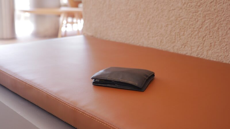 Black leather wallet left on a brown leather bench