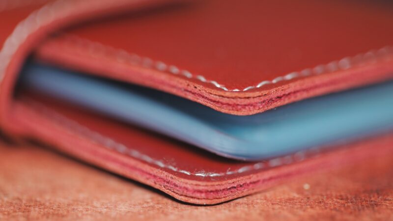 Close-up of a red leather wallet edge with visible layers and stitching