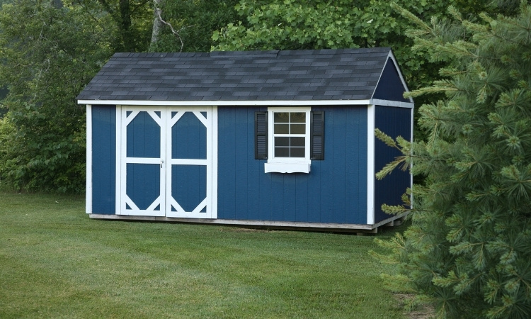 Blue backyard shed with white trim standing on a grassy residential property.