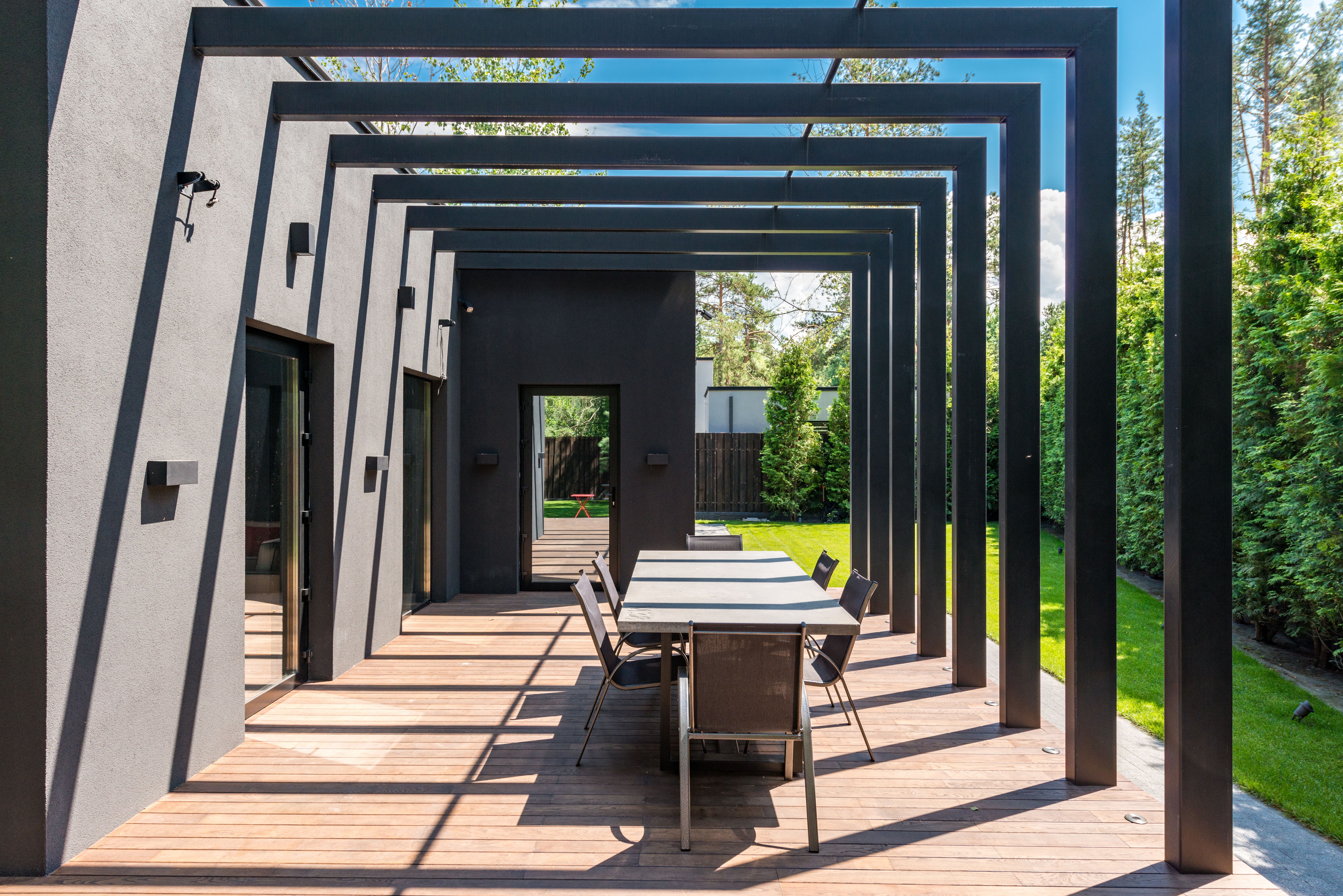 Contemporary pergola over an outdoor dining area in a landscaped garden