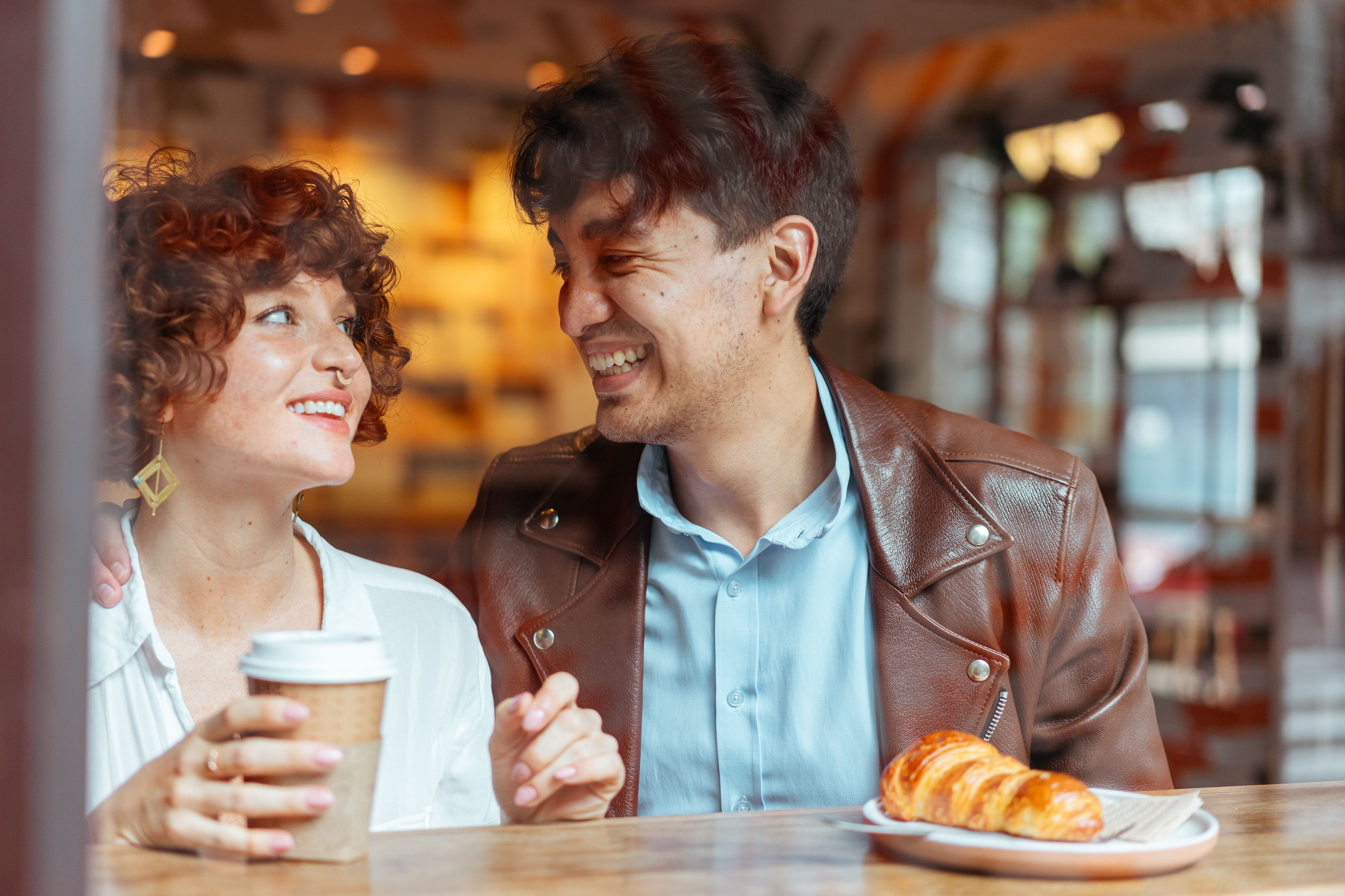 A couple laughing together over coffee at a cozy cafe, capturing relaxed traditional dating.